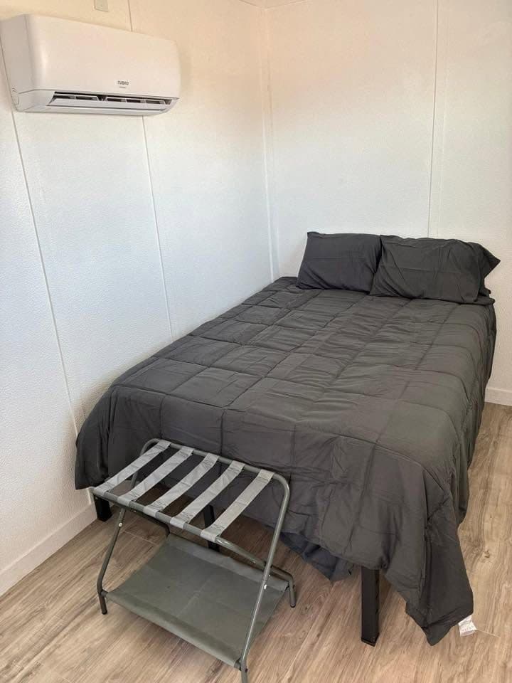 Furnished bedroom in a container unit with a wall-mounted mini-split heat and air unit