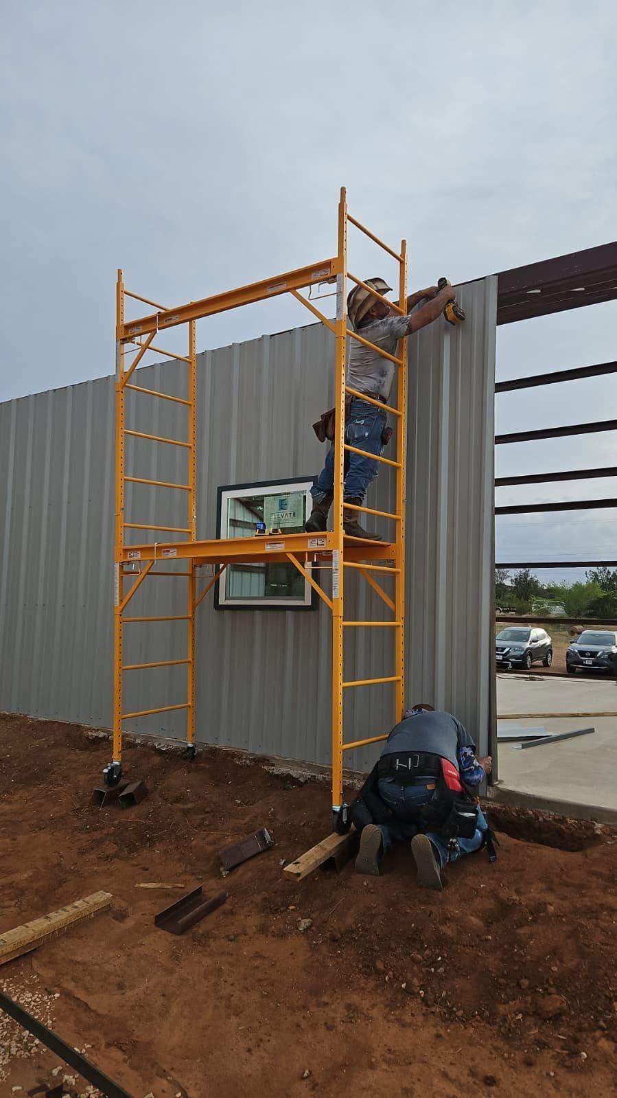 Crew installing wall panels on a metal building from scaffolding