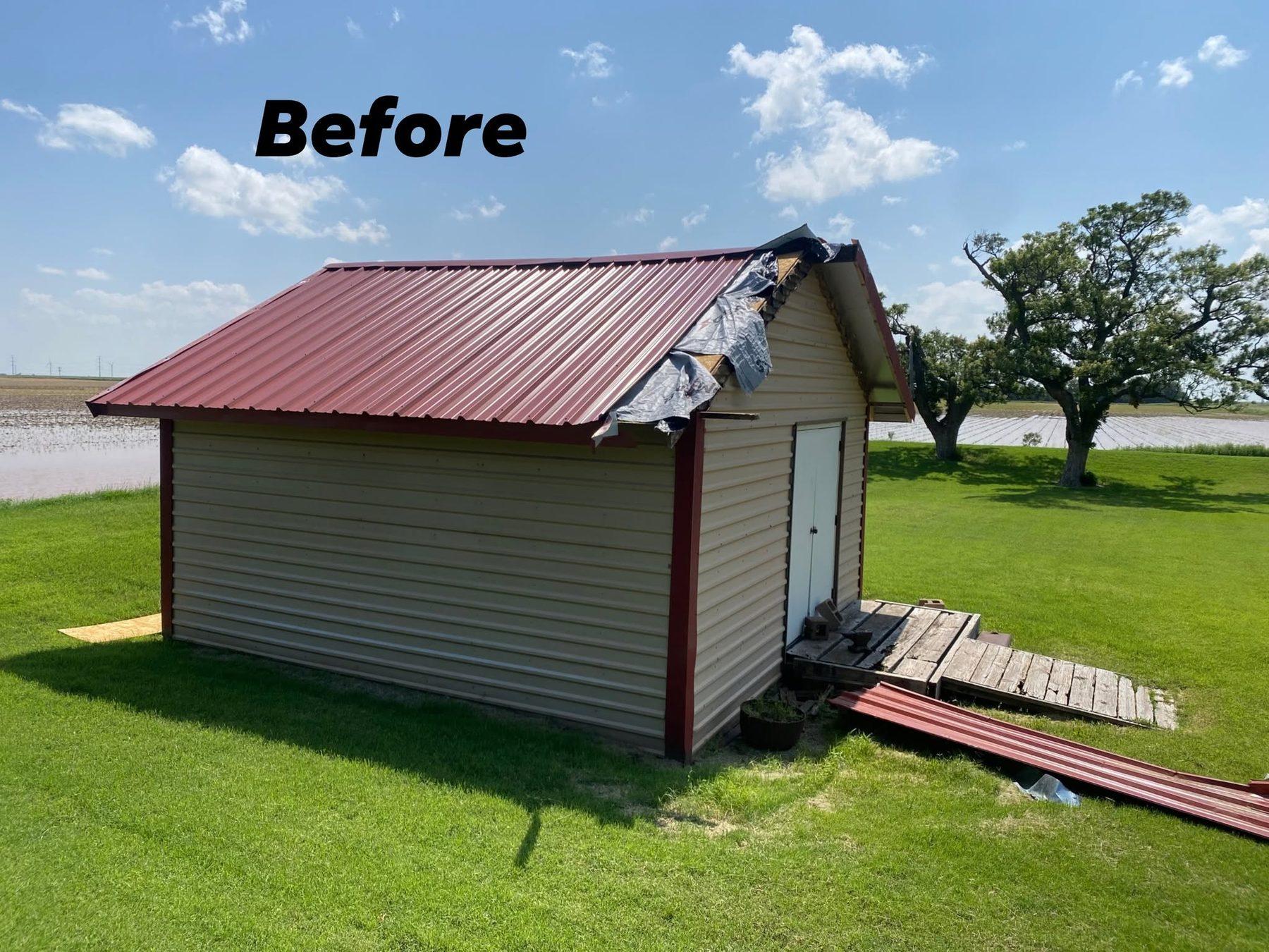 A barn with torn red metal roofing and downed panels, before repair