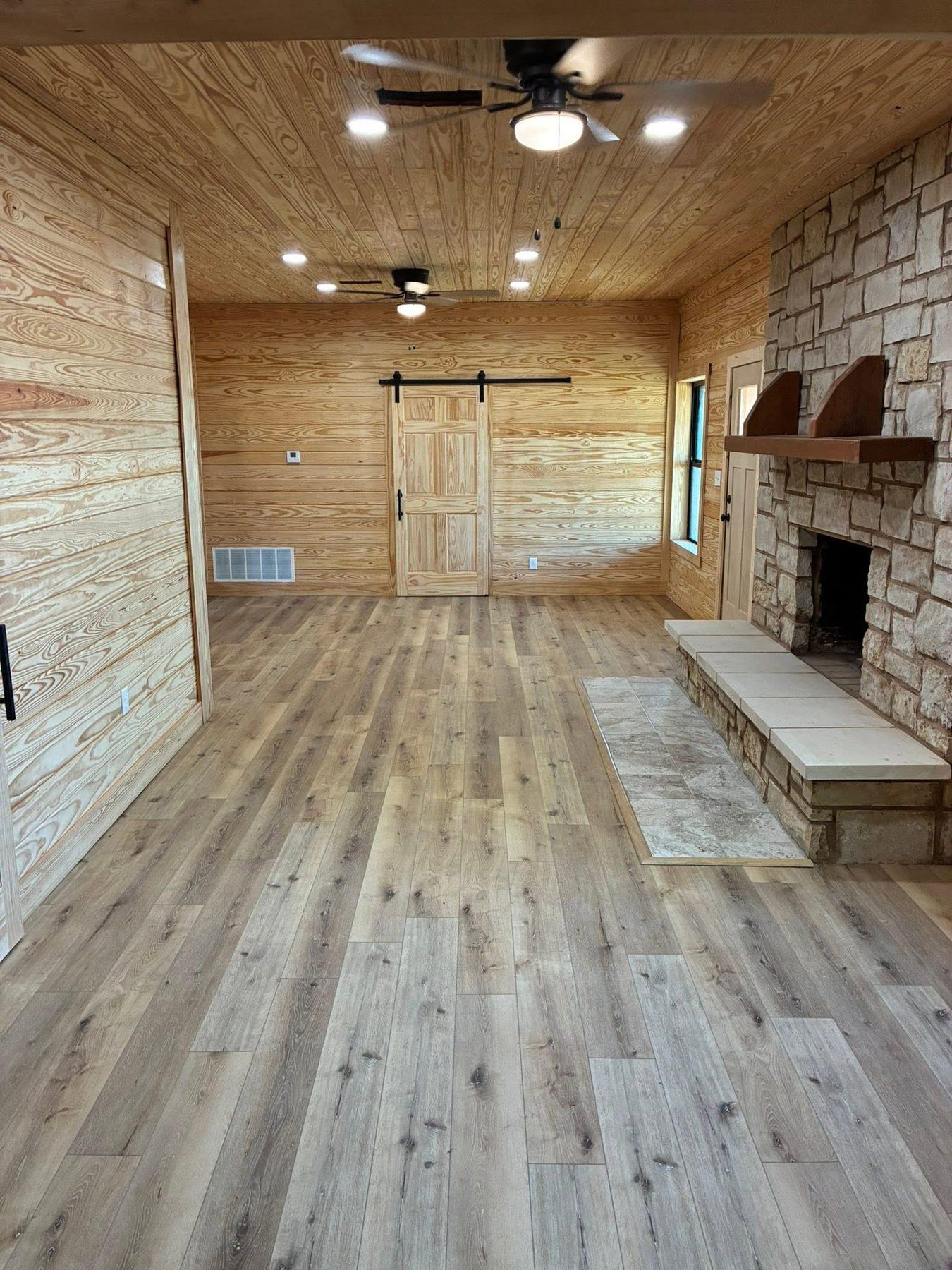 Finished interior with pine walls, a stone fireplace and wood flooring